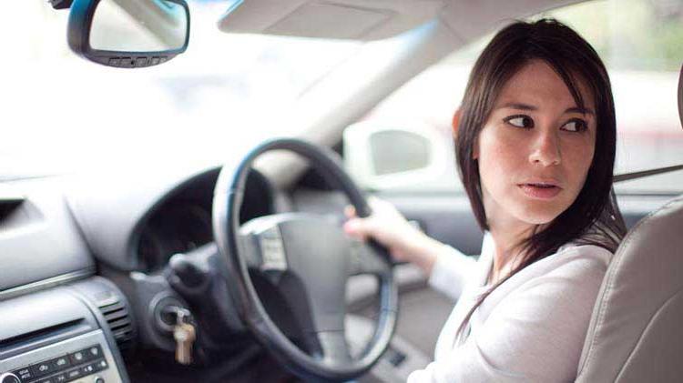 Woman looking behind her while backing up her car.